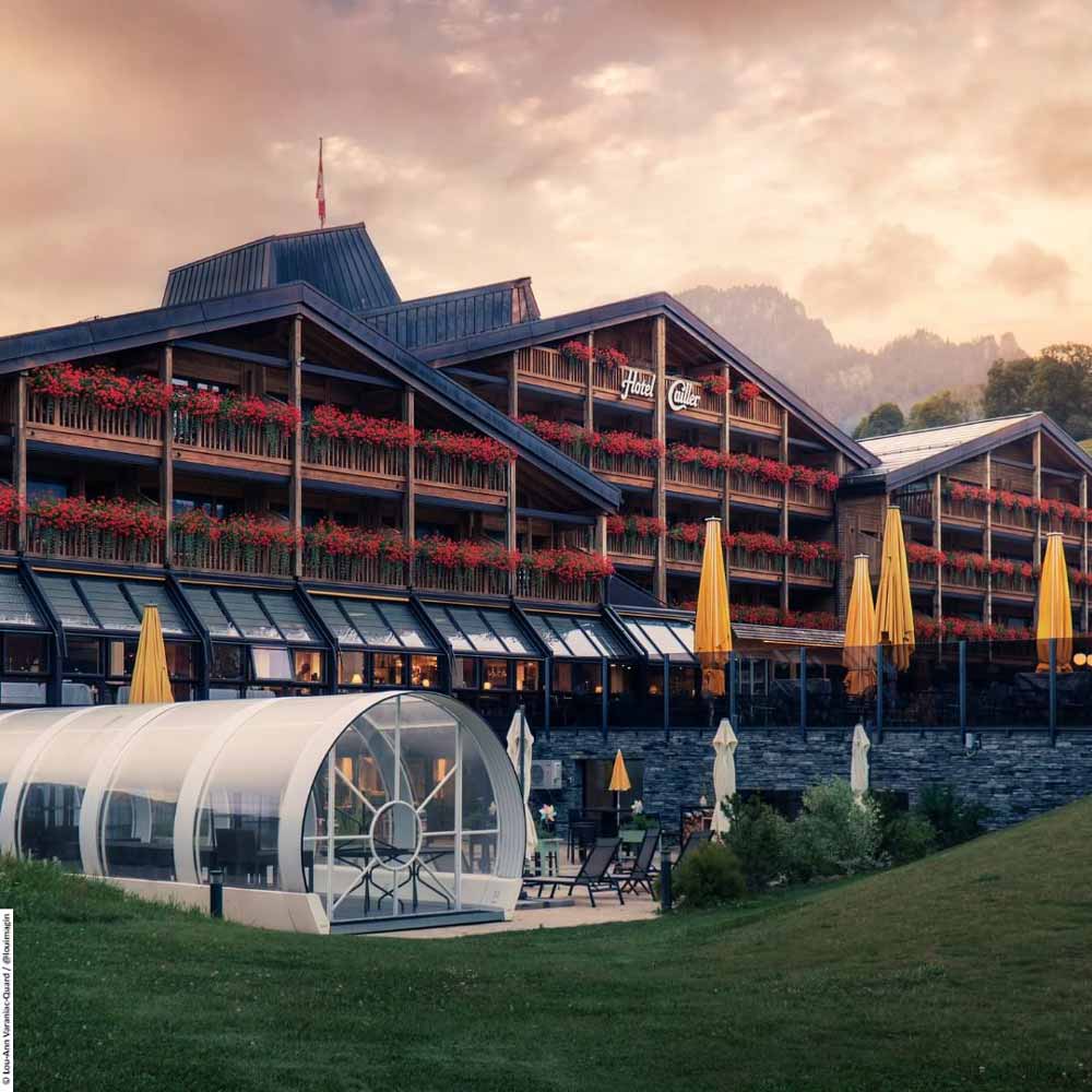 Elegant hotel building with balconies and vibrant flower arrangements under a sunset sky.