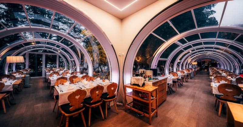 Modern glass-enclosed restaurant interior with elegant seating and ambient lighting for dining and events.