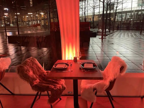 Luxurious restaurant interior with cozy fur-covered chairs and modern decor, illuminated by warm lighting.