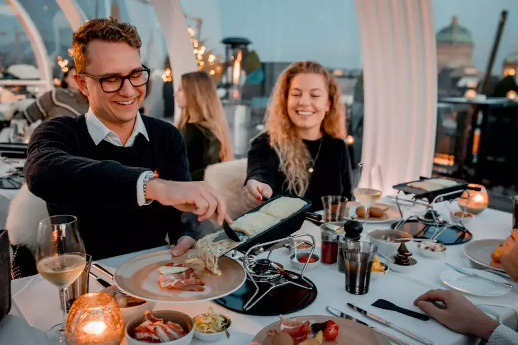 Elegant dining at rooftop restaurant with friends, enjoying gourmet cheese fondue, wine, and sunset views.
