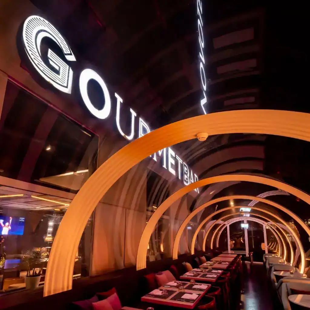 Modern restaurant interior with illuminated signage and circular architectural design elements, creating a stylish dining atmosphere.