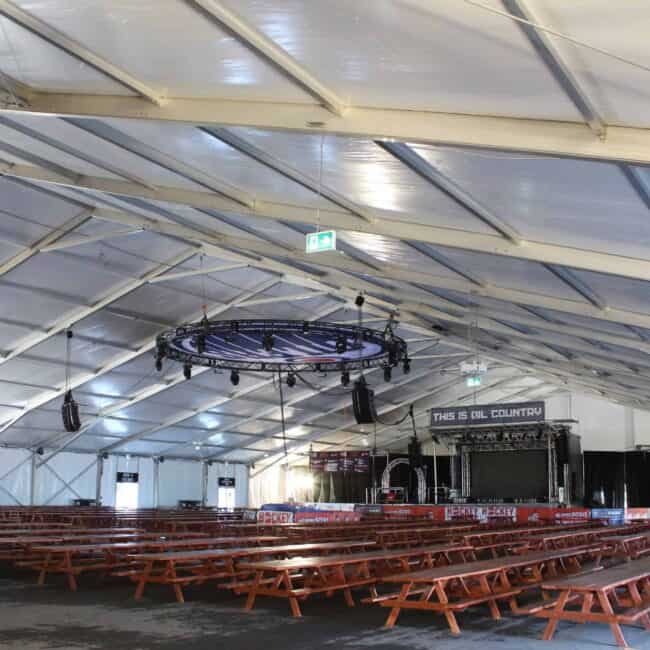Indoor event tent featuring seating, stage, and lighting for sports and entertainment events.