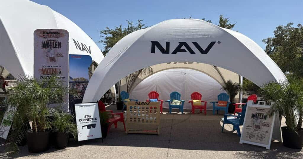 Bright outdoor event tent with NAV branding, showcasing modern seating, promotional displays, and potted plants at EJH Distribution.