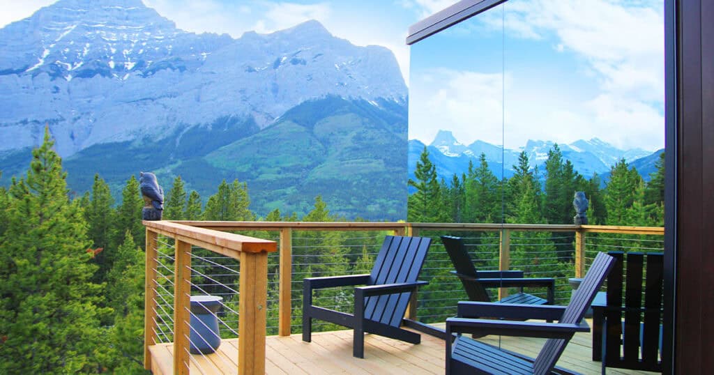 Mountain view outdoor balcony with wooden deck, black chairs, and scenic forest landscape, perfect for relaxation and enjoying nature.