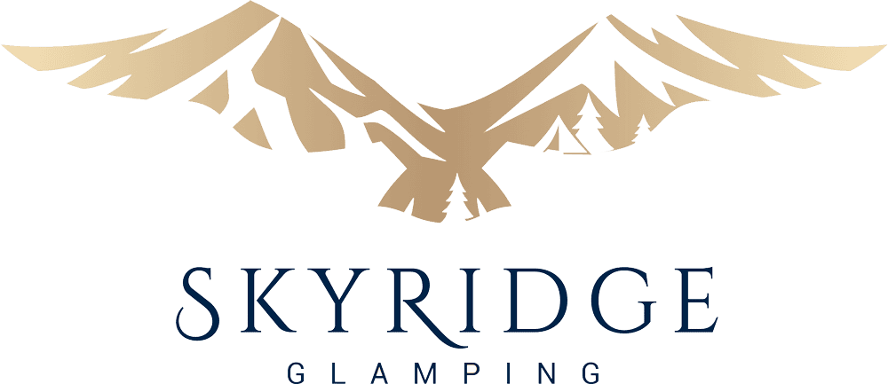 Scenic view of SkyRidge glamping site featuring cozy tents nestled among mountains, offering outdoor adventure and luxury camping experience.