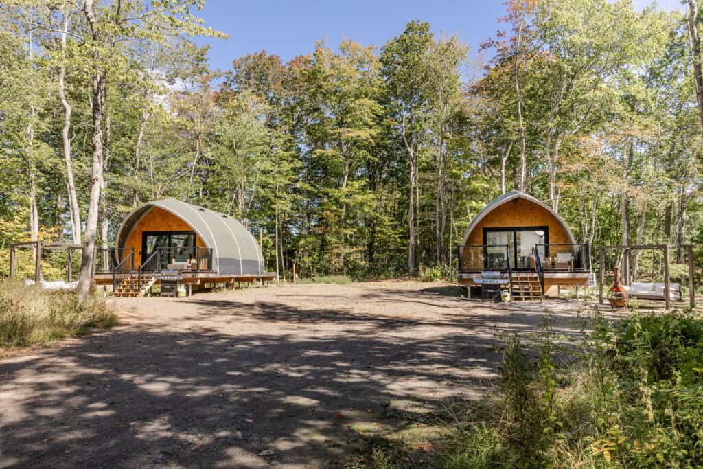 Two modern glamping tents nestled among trees in a peaceful forest. Perfect for outdoor adventure, nature escape, and eco-friendly travel experiences.